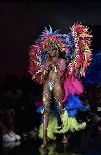 a woman in a colorful costume walks the runway