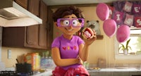 a girl in glasses is holding a donut in a kitchen