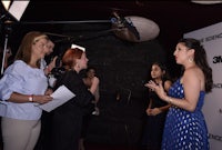 a group of people talking on a red carpet at an event