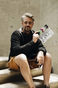 a man sitting on steps holding a clapper board