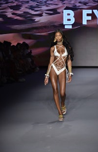 a model walks the runway in a white bikini