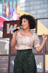 a woman with curly hair singing into a microphone