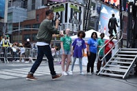 a group of people standing on a stage in times square