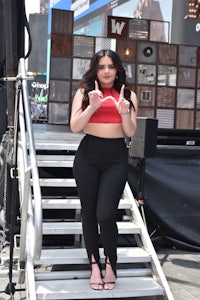 a woman in black pants and a red top posing for the camera