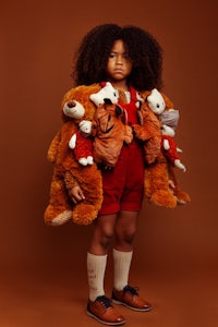 a young girl holding teddy bears on a brown background