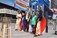 a group of people standing in front of a sign in times square