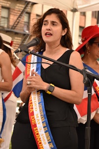 a woman wearing a sash with a flag in front of her