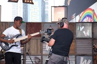 a young man playing a guitar in front of a camera