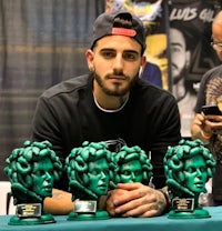 a man is standing next to a table full of green medusa statues