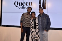 three men standing in front of a queen collection sign