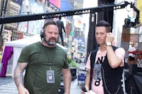 two men standing in front of a camera in times square