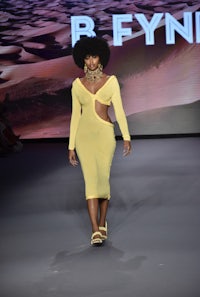 a woman in a yellow dress walks down the runway