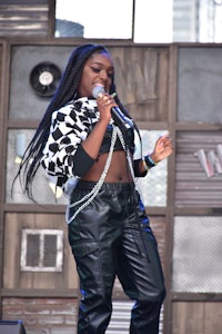 a woman in black leather pants singing into a microphone