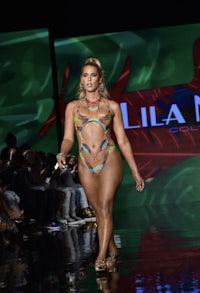 a woman in a bikini walks the runway at a fashion show