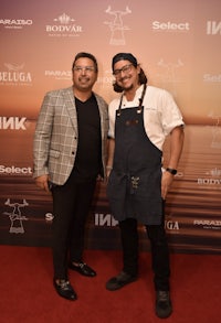 two men standing next to each other on a red carpet