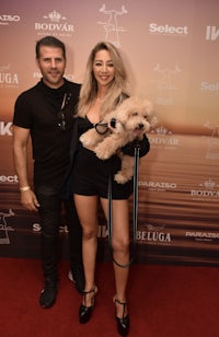 a man and woman posing with a dog on a red carpet