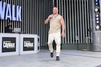 a man in a tan shirt standing in front of a sign