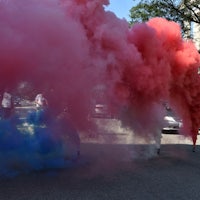 a group of people blowing up pink and blue smoke