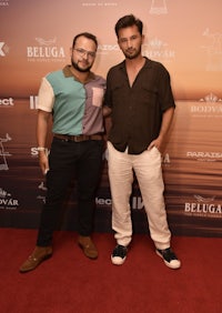 two men standing next to each other on a red carpet