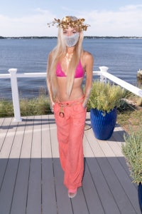 a woman in a pink bikini standing on a deck next to the water