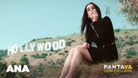 a woman sitting in front of a hollywood sign