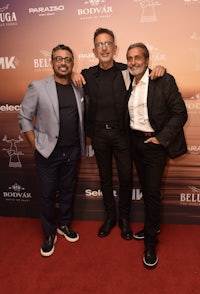 three men posing on a red carpet at an event